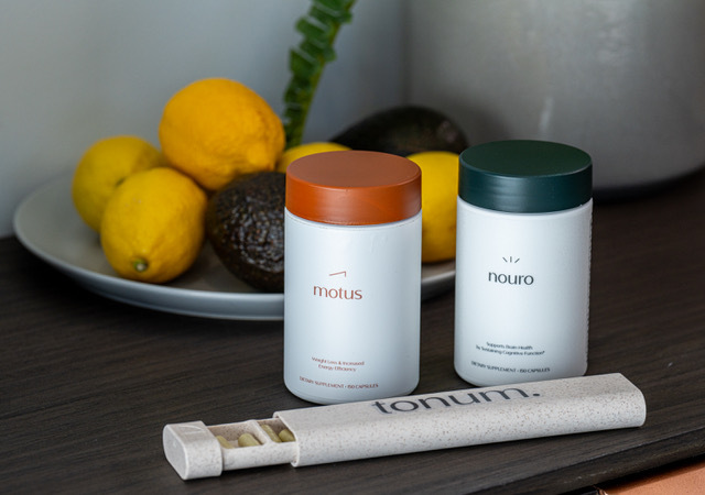 containers of motus and nouro supplements and a pill organizer case next to a bowl of fruit