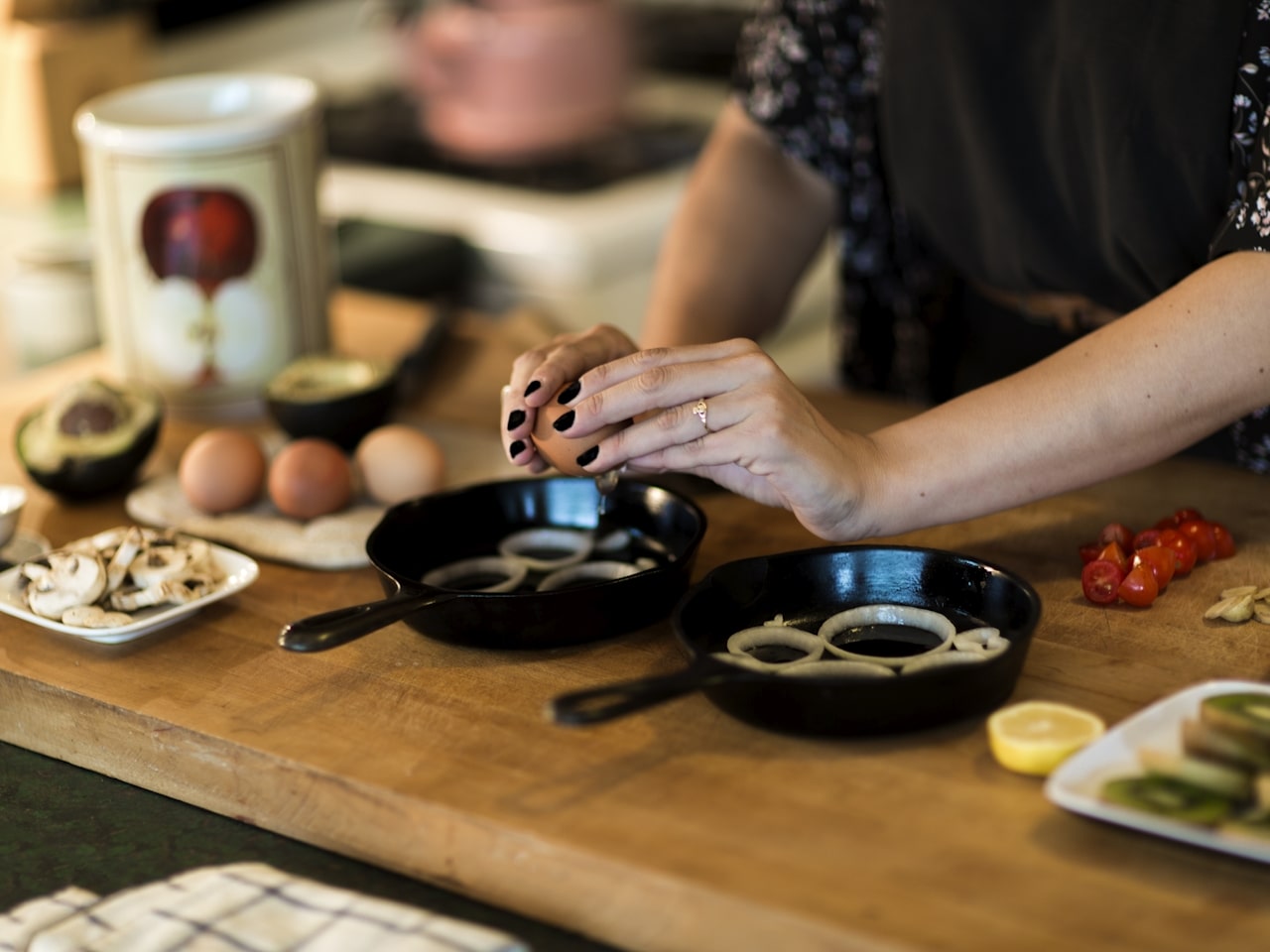 person cracking egg into cast iron skillet on kitchen butcher block
