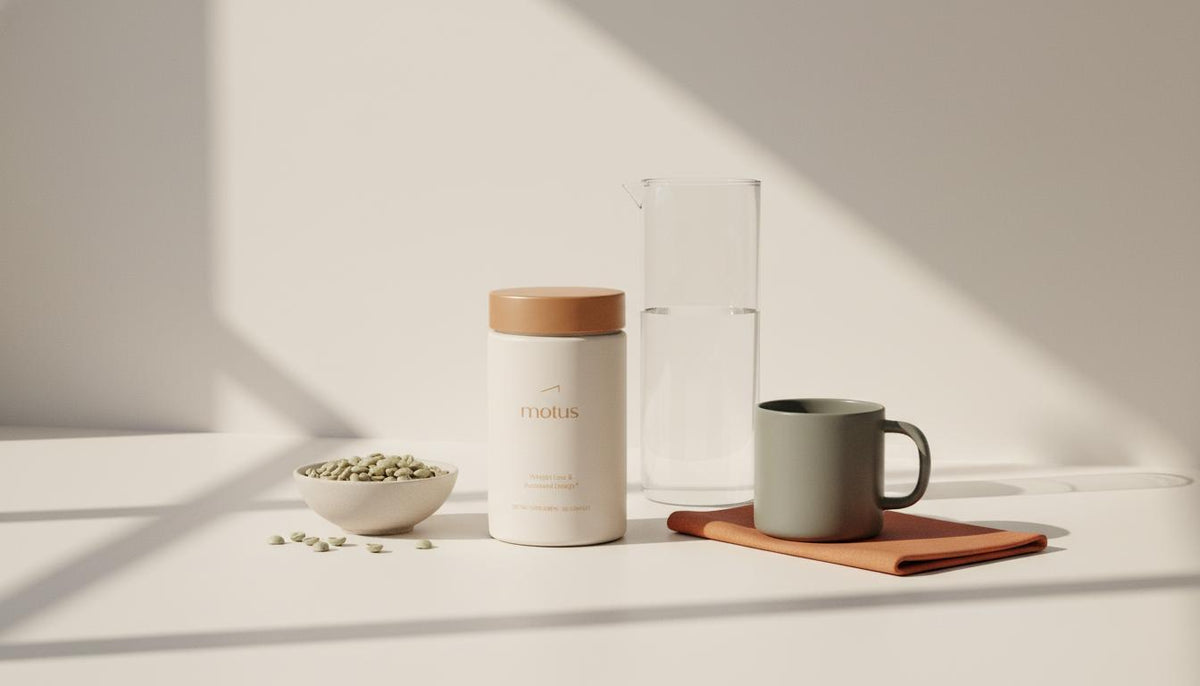 Tonum supplement jar beside a bowl of unroasted green coffee beans, glass carafe and ceramic mug on a minimalist countertop with soft natural light, green coffee.