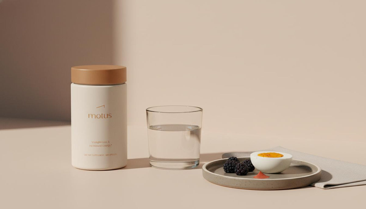 Minimalist lifestyle photo of Tonum Motus container beside glass of water, plate with egg and berries on beige surface, soft side light — best appetite suppressant supplements