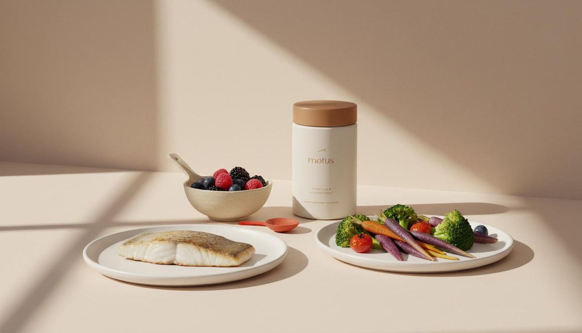 Minimalist kitchen counter with plate of colorful vegetables, a small fish fillet, bowl of berries and a Motus supplement bottle — best foods for weight loss