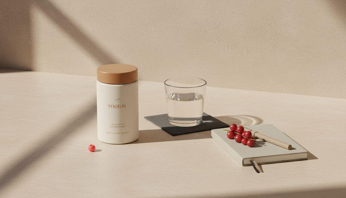 Minimalist countertop with Tonum Motus supplement jar beside a glass of water, a closed notebook and a sprig of fresh berries, styled for a garcinia cambogia health article.