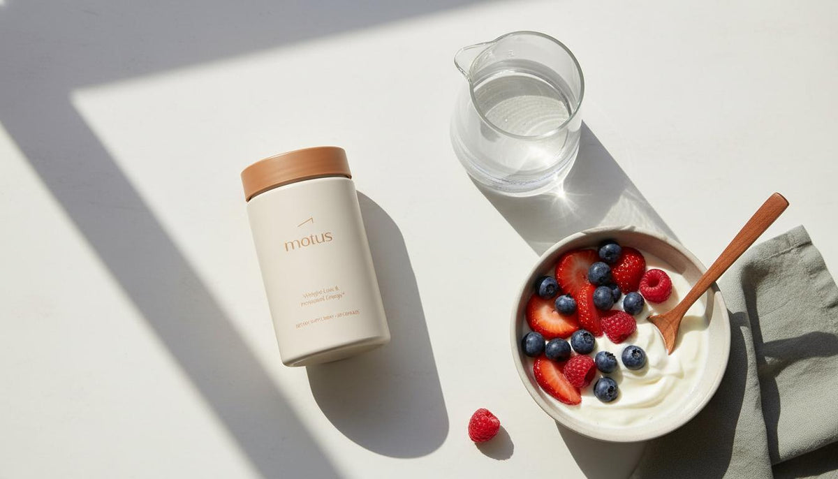 Top-down minimalist kitchen scene with Tonum Motus container, carafe of water and Greek yogurt bowl showing how to make hunger go away naturally.