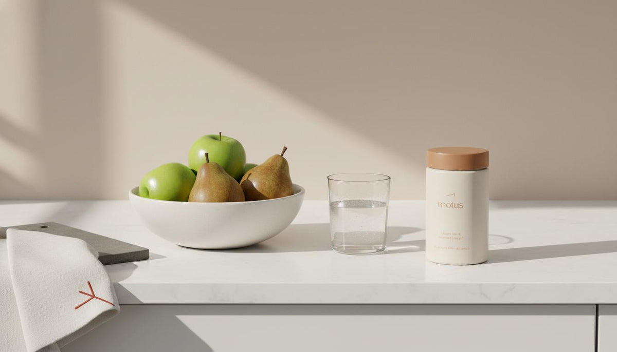 Minimal kitchen counter still-life with bowl of whole fruit, glass of water and Tonum Motus container, evoking practical wellness to stop sugar cravings naturally.
