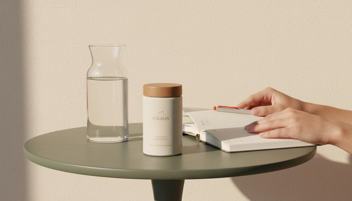 Sunlit minimalist scene with Tonum Nouro container on a round table beside a glass carafe and journal, hands opening the journal in the background — vitamin cuts dementia risk