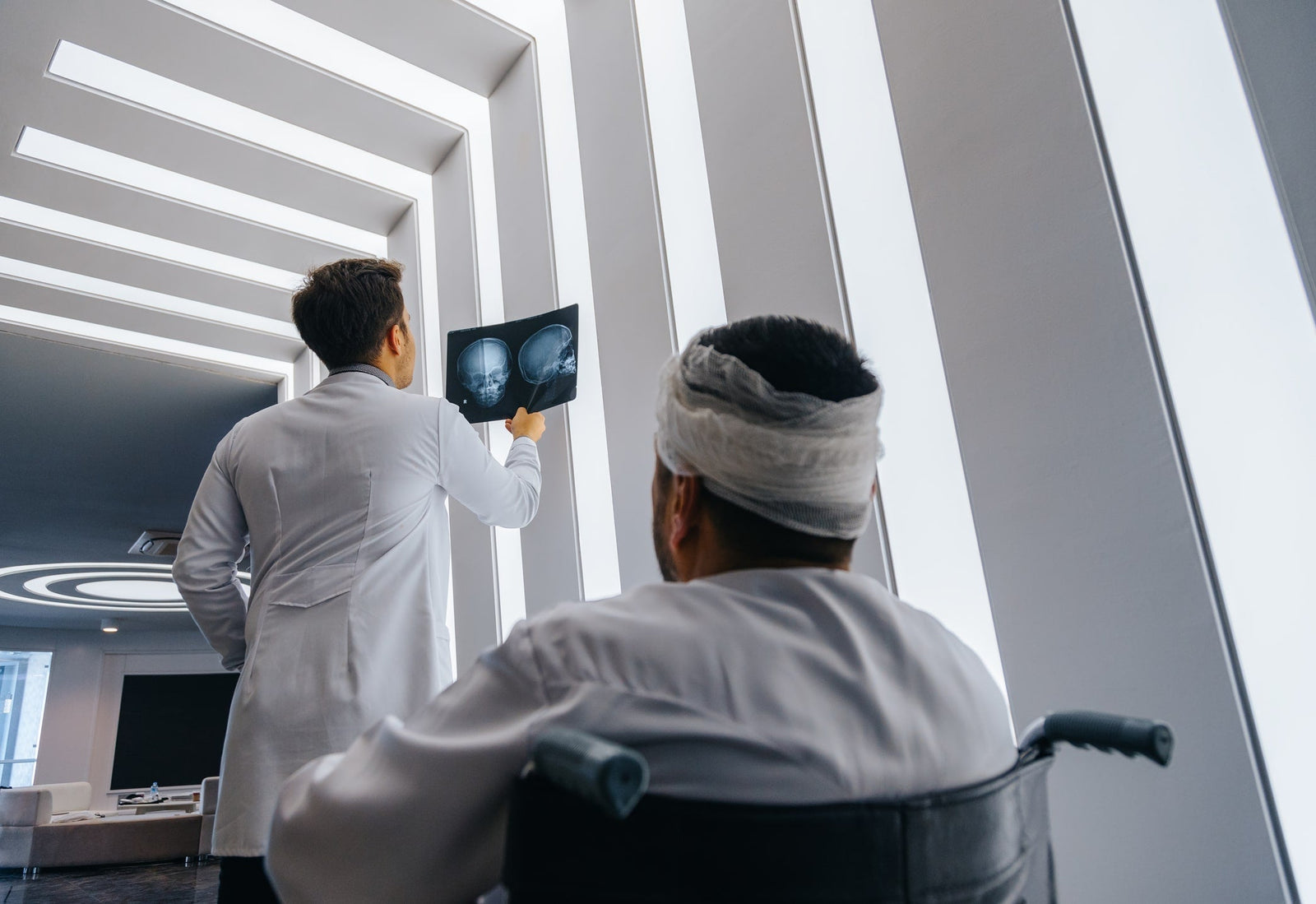 doctor looking at mri scan results next to head injury patient in wheelchair