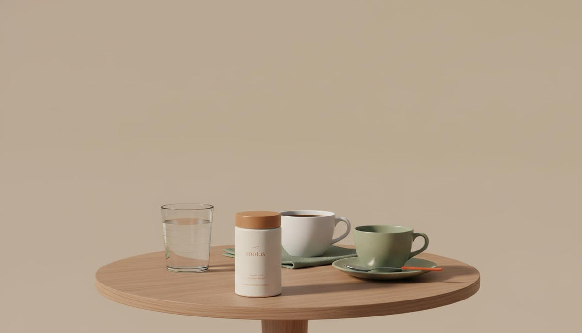 Minimalist still-life: 8oz glass of water, white coffee cup, green tea cup and Tonum Motus container on a wooden table against beige background — Which drink reduces liver fat