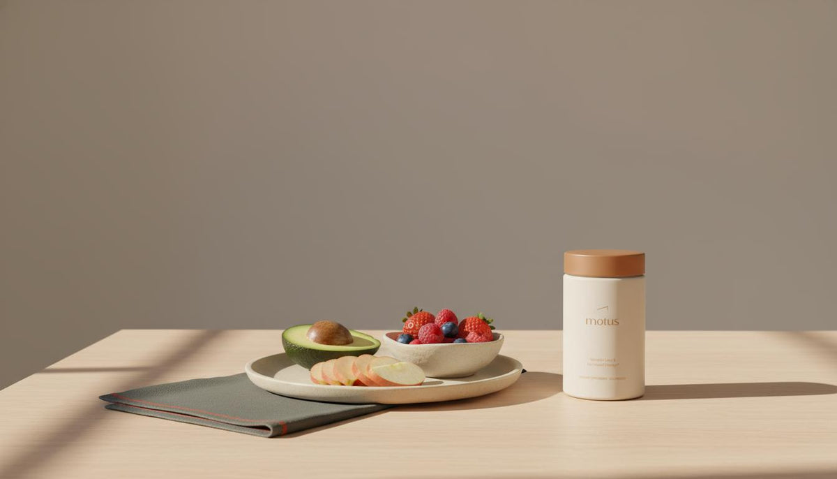 Minimalist photo of mixed berries, a sliced apple and half avocado on a wooden table with Tonum supplement container, illustrating which fruit reduces appetite