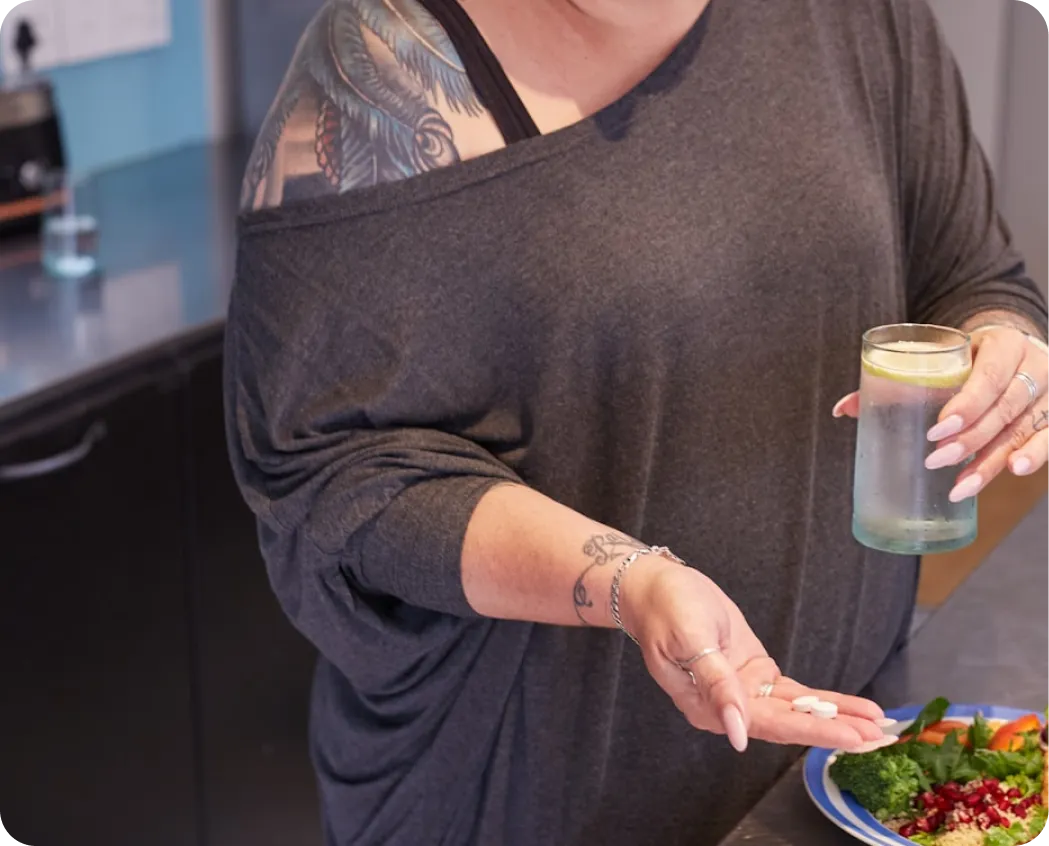 Woman holding Motus capsules and a glass of water